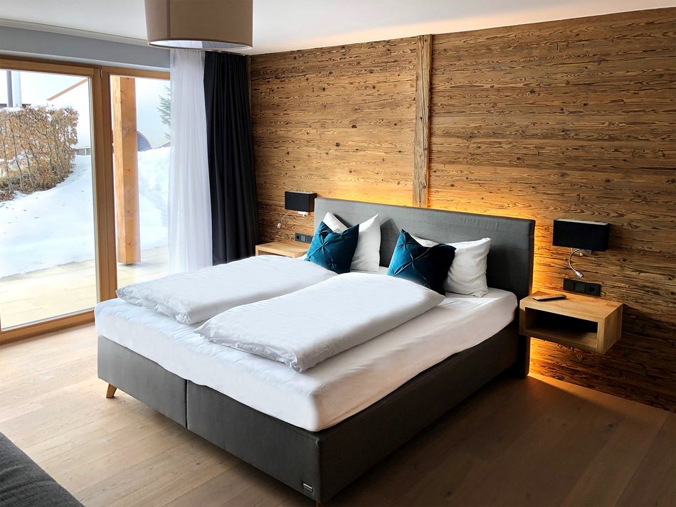 Schlafen in harmonischer Atmosphäre in der Maisonette-Ferienwohnung Almwiese in Seefeld Schlafzimmer mit Doppelbett vor Holzvertäfelung in der Maisonette Almwiese in Seefeld, Tirol